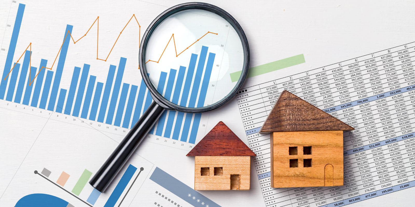Table with magnifying glass, toy house and graphs about real estate market